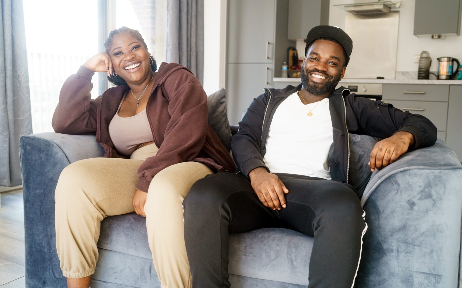 Jenelle and AJ smiling on the sofa in their East London flat